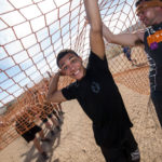 Participants standing up to hold the net for their teammates who are crawling